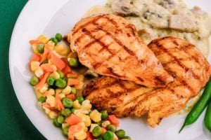 This photo is of a dinner plate with baked chicken breasts and mixed vegetables.