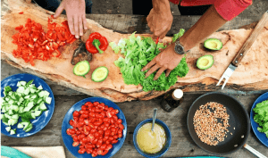 Photo shows dishes of colorful food and a pair of hands chopping lettuce.