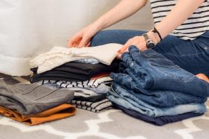 Photo shows a young woman folding laundry.