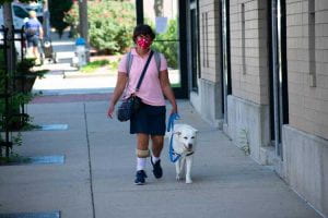 Adria walks with Lucy on a sidewalk.