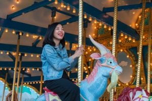 young girl riding a unicorn on a merry-go-round.