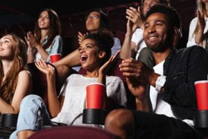 Young people in a movie theater laughing and clapping their hands.