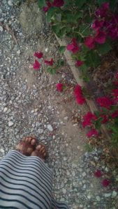 A person's feet as they stand on gravel next to flowers