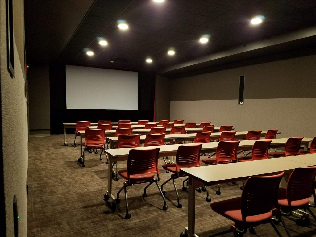 Chairs and tables lined up in front of a big screen