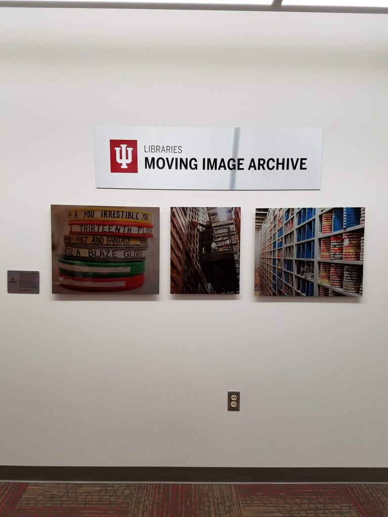 Three photos and a sign on the wall outside the Moving Image Archive