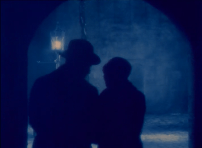 blue-tinted screenshot of silhouetted couple walking toward a street lamp