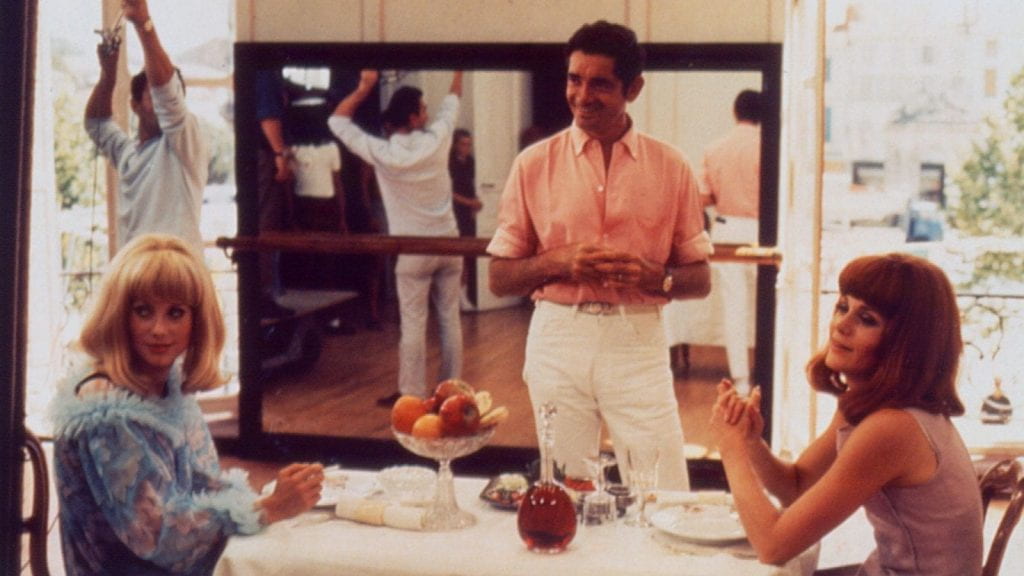 From left to right: Catherine Deneuve, Jacques Demy, and Françoise Dorléac on set.