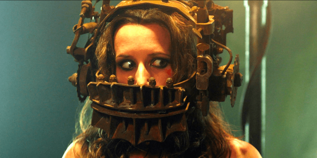 A terrified woman sits with her whole head encased in a deadly metal contraption
