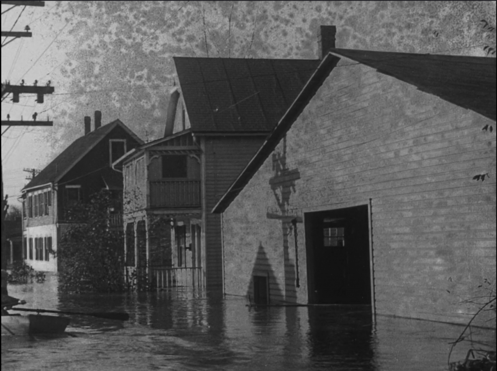 speckles of film deterioration on a scene of flooded buildings