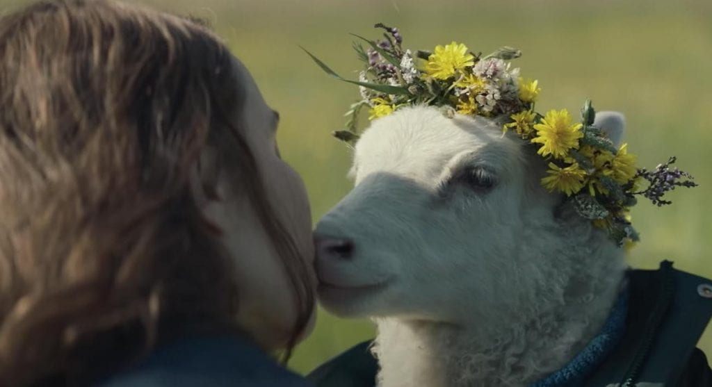 Maria gives Ada the lamb a kiss on the cheek while Ada wears a flower crown
