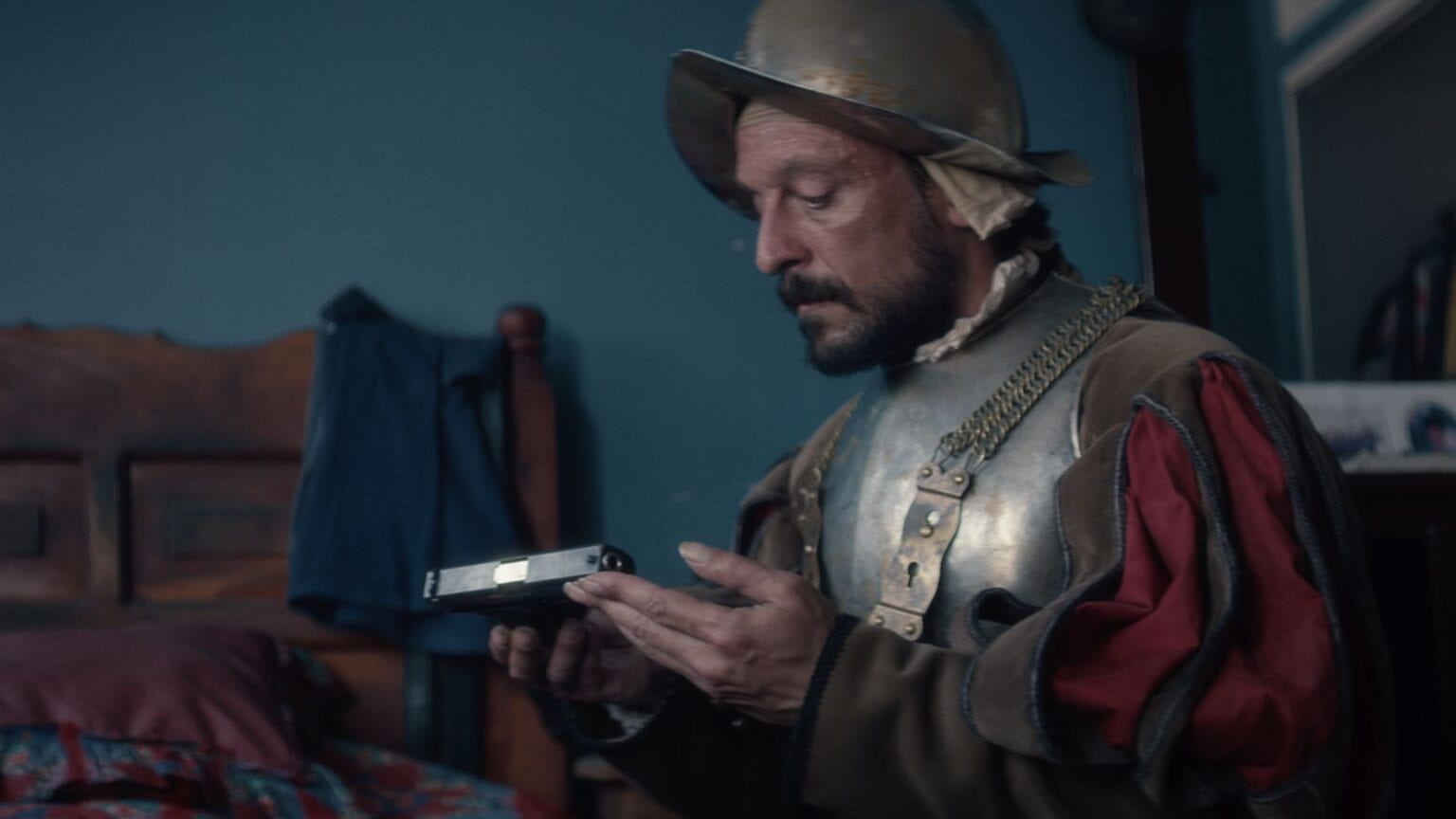 A conquistador holds and looks at a gun