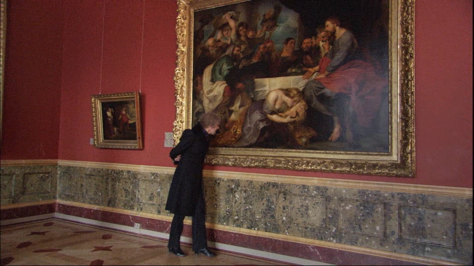 A man stands in front of a large painting