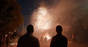 Two men stare at a big firecracker in the sky