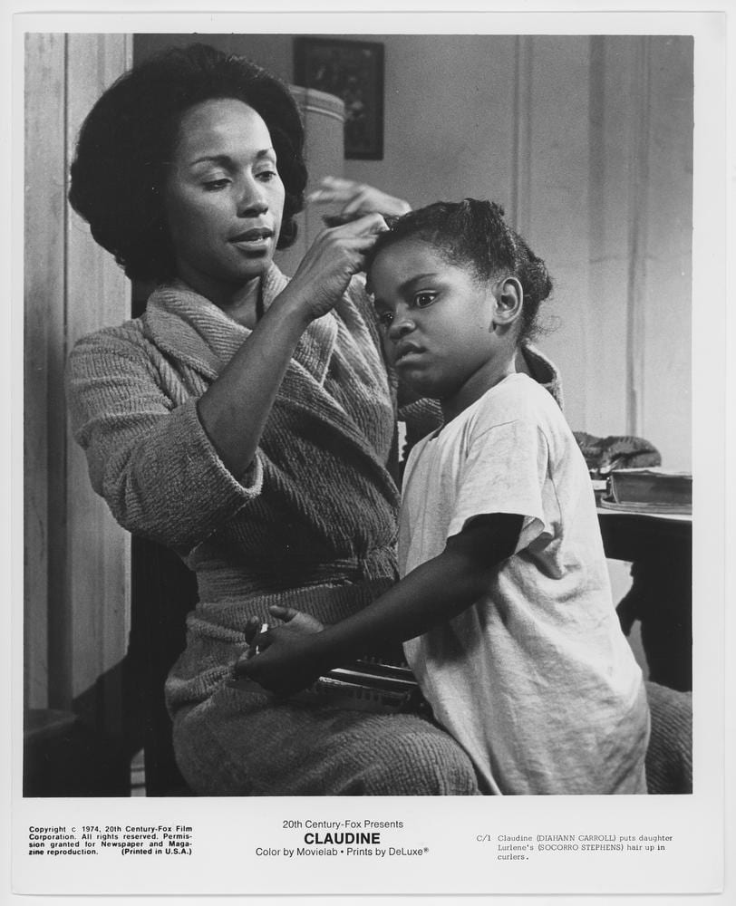 Black and white image of a woman fixing the hair of her small daughter