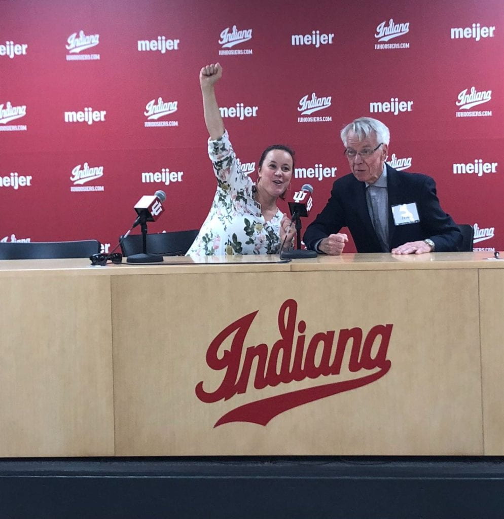 A man and woman sit behind a desk that says "Indiana" at an event