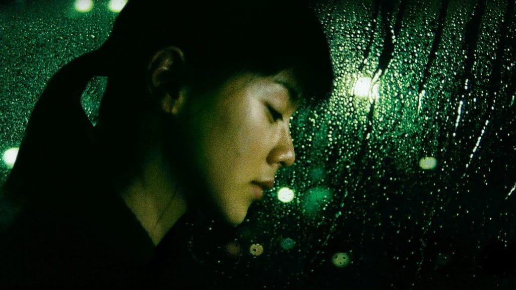 A woman leans her head against a rain-soaked window