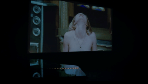 A screen depicts a nude woman in a scene from Salo