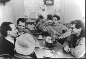A group of men smile and talk around a table in a diner