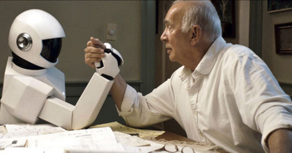 A white robot arm-wrestles with an elderly man