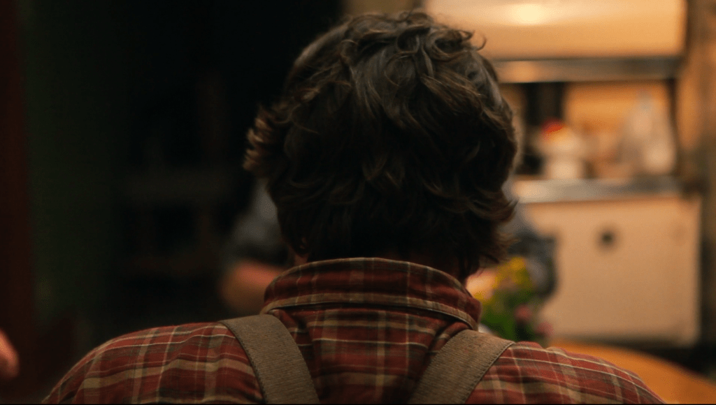 The back of Jeremiah's head. He has brown hair and wears a plaid shirt and suspenders.