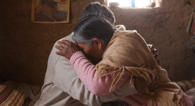 An elderly man and woman embrace each other