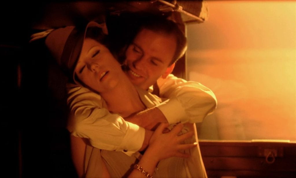 A man embraces a woman from behind in a train car
