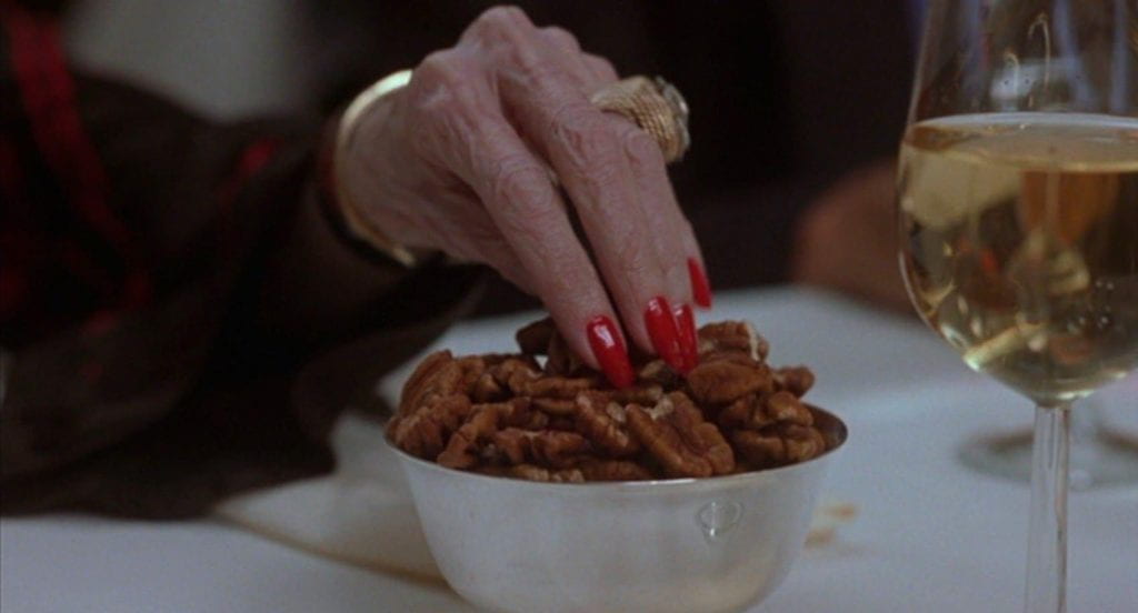 Close-up of an elderly woman's hand as she touches a bowl of pecans