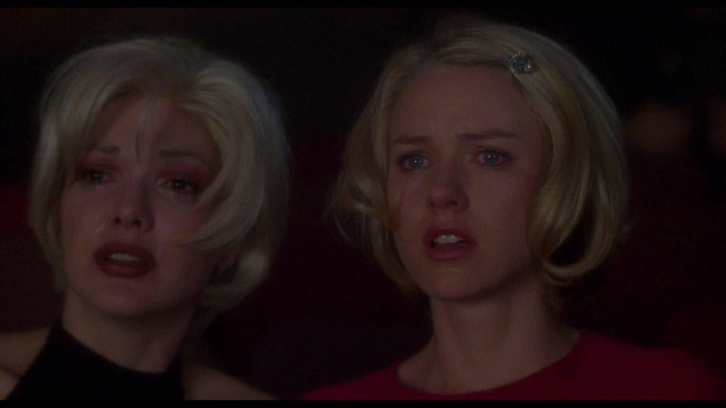 Medium close-up of Betty and Naomi watching the stage in a darkened theater