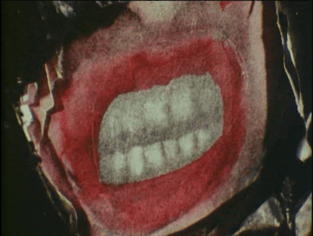 Close up of a paper ripping away to reveal a photo of snarling mouth, lips peeled up wide revealing both rows of clenched teeth