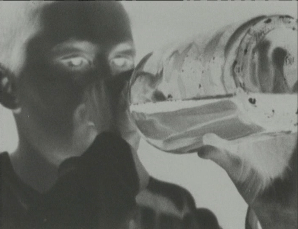 photographic negative image of a woman drinking from a large bottle of wine. She holds it with both hands.