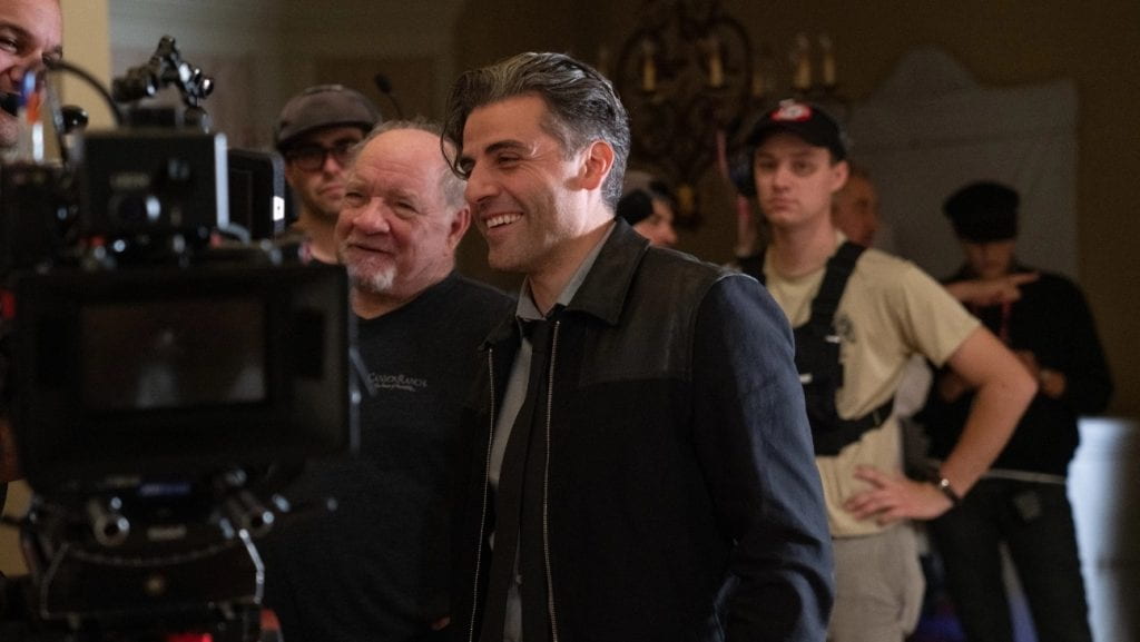 Paul Schrader and Oscar Isaac smile behind the camera on the set of The Card Counter