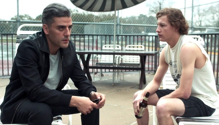 Oscar Isaac and Tye Sheridan sit on pool lounge chairs, not looking at each other