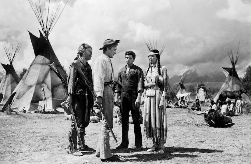 A group of white men stand with a Native woman on a reservation