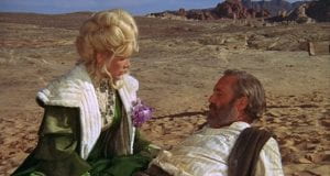 Stella Stevens looks down at a reclining Jason Robards outside in a western setting