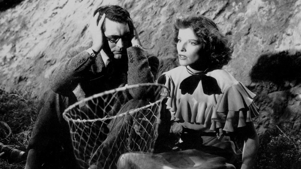 An exasperated Cary Grant looks at Katharine Hepburn as she holds a butterfly net