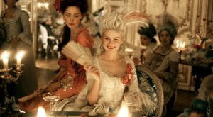 Kirsten Dunst as Marie Antoinette smiles with a fan in her hand