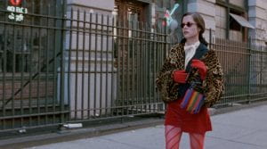 Parker Posey walks down a city street in a colorful, fashionable outfit