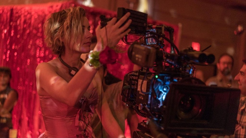 Greta Gerwig wearing a prom dress as she directs the prom scenes in Lady Bird