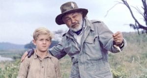 Edward G. Robinson shows a small boy something offscreen in a field