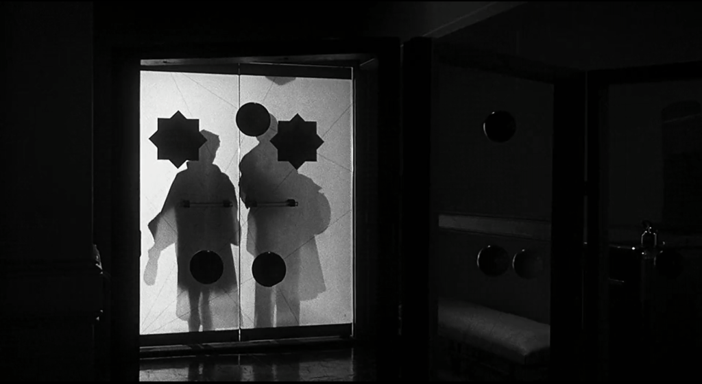 A man and woman's bodies are silhouetted behind a pair of frosted glass doors