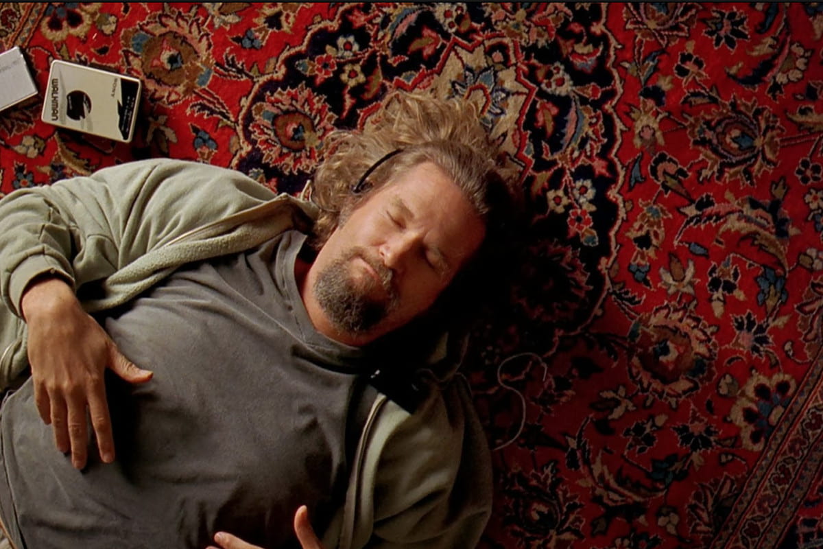 Jeff Bridges lays on a rug while listening to music with his eyes closed