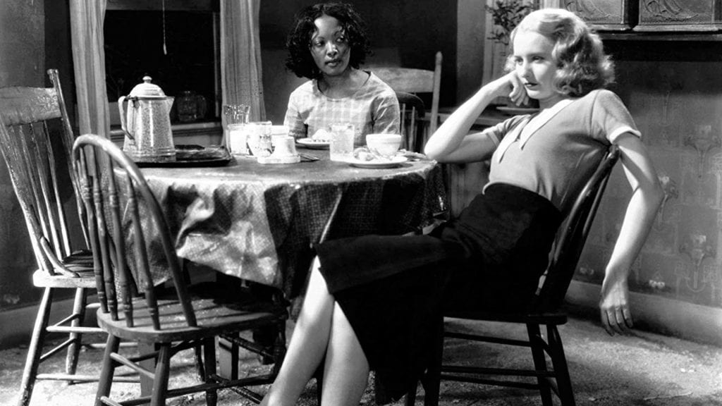 Theresa Harris and Barbara Stanwyck sit at a table together