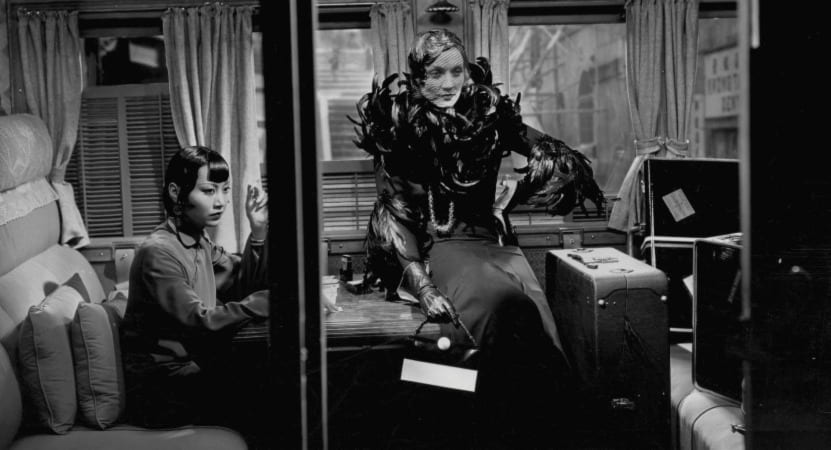 Anna May Wong and Marlene Dietrich sit in a train car together
