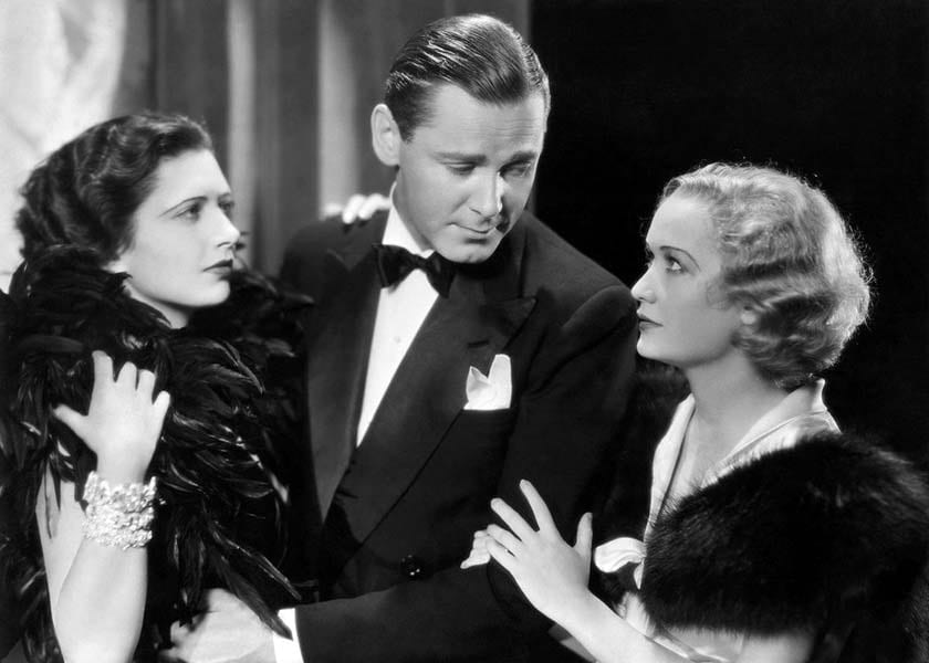 Kay Francis and Herbert Marshall hold onto one another as he looks at Miriam Hopkins beside him