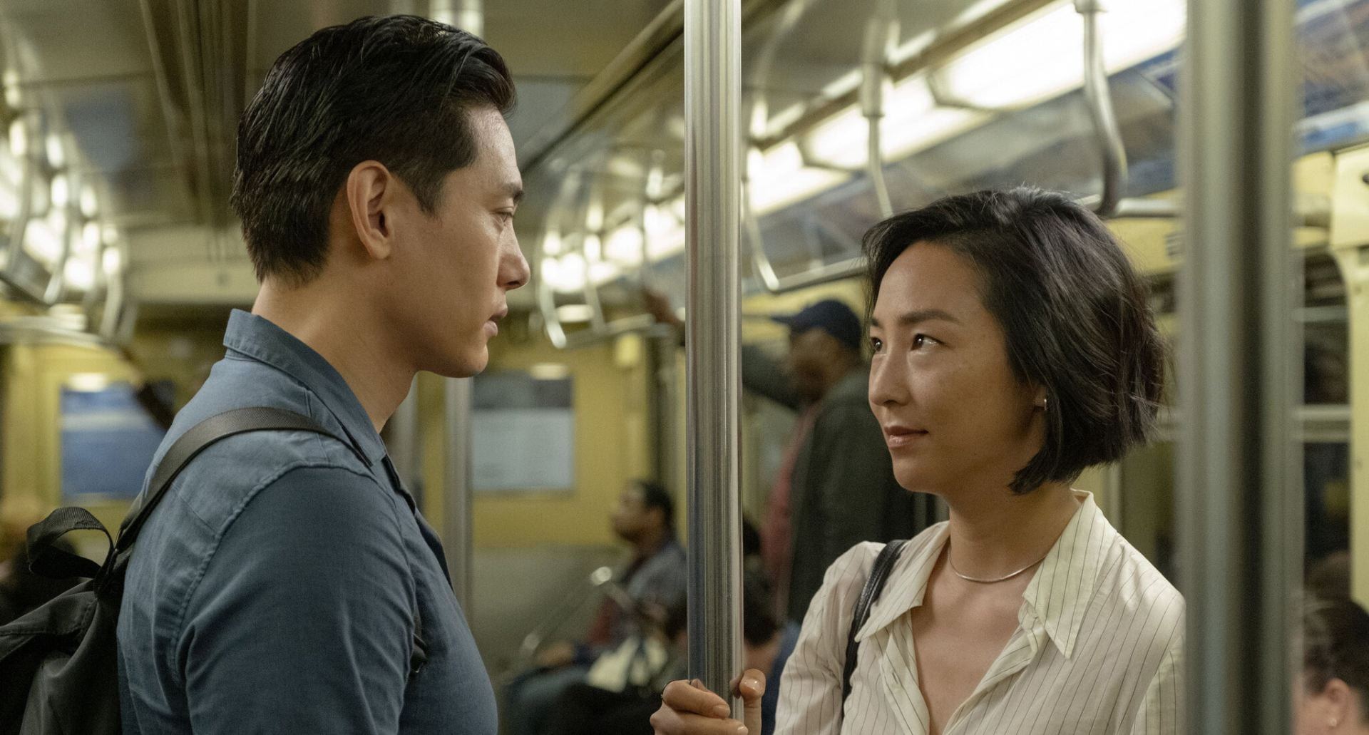 A man and woman look at each other in a subway car