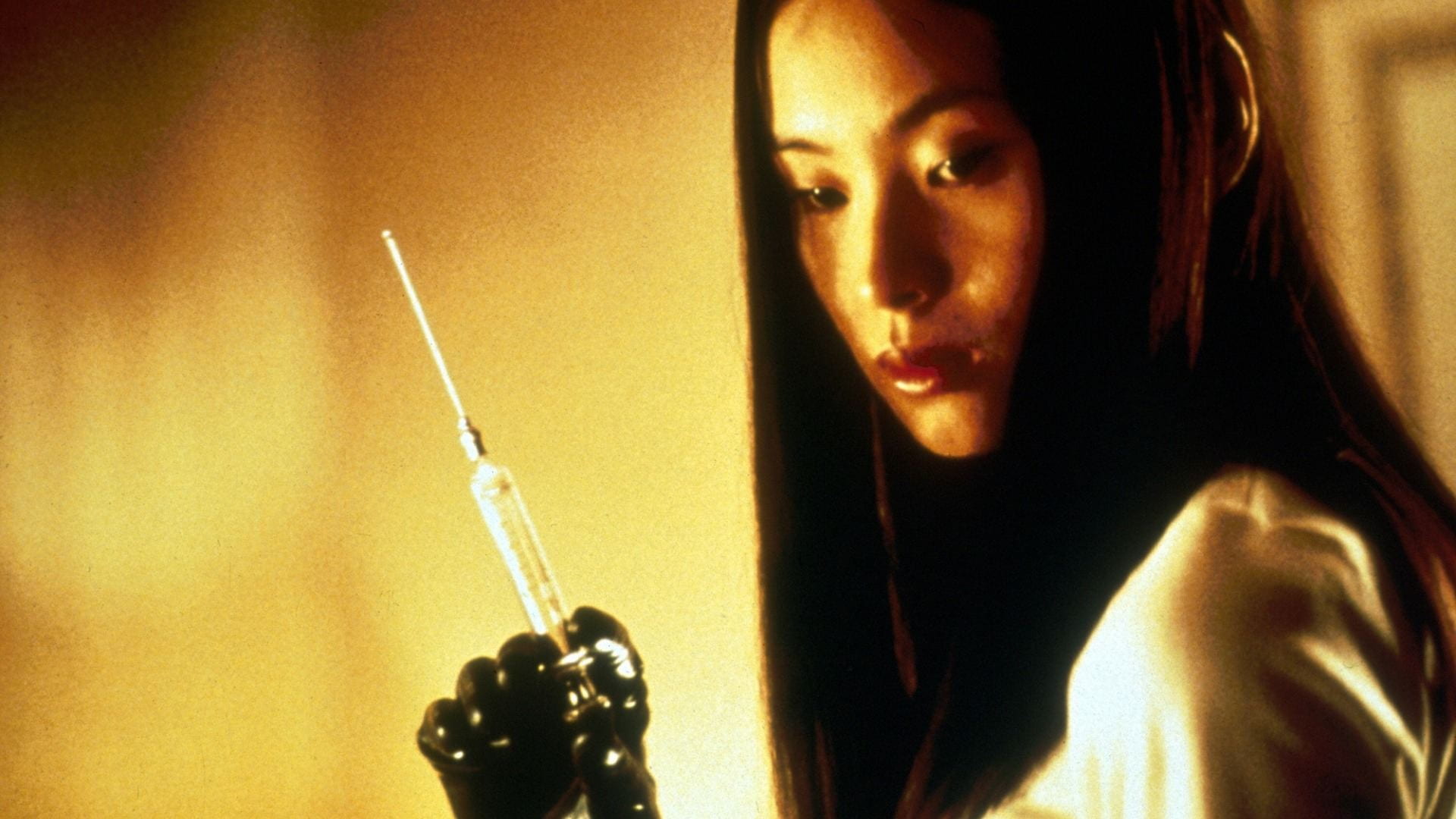 A young woman looks down and holds up a syringe with a long needle