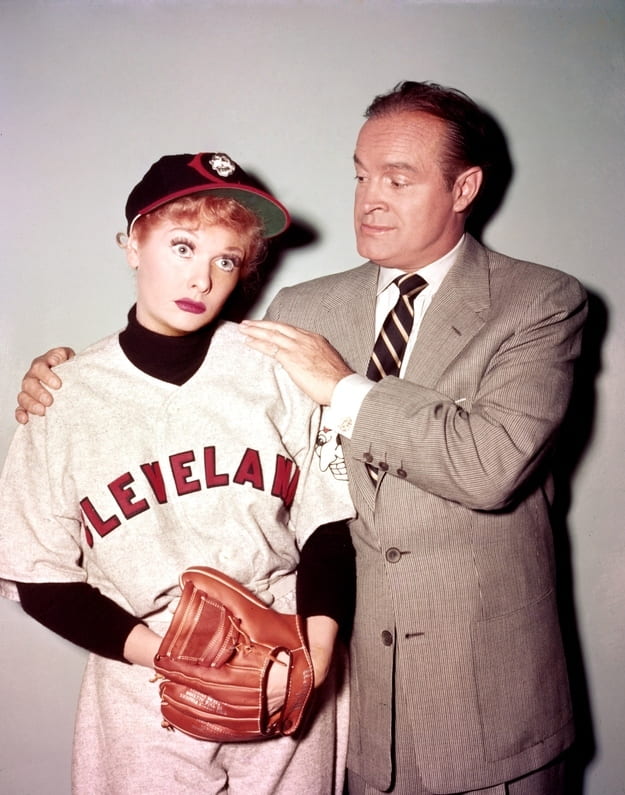 Bob Hope puts his hands on Lucille Ball's shoulders as she looks downtrodden in a baseball uniform