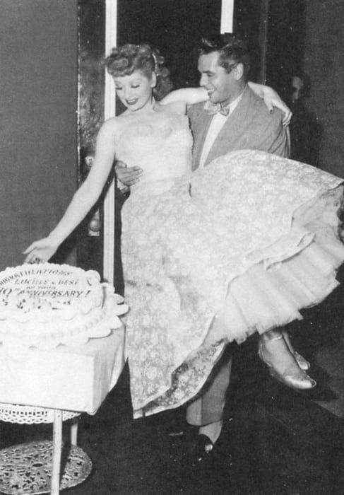 Desi Arnaz carries Lucille Ball as they look down at a big cake