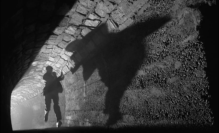 A man runs down a shadowy tunnel