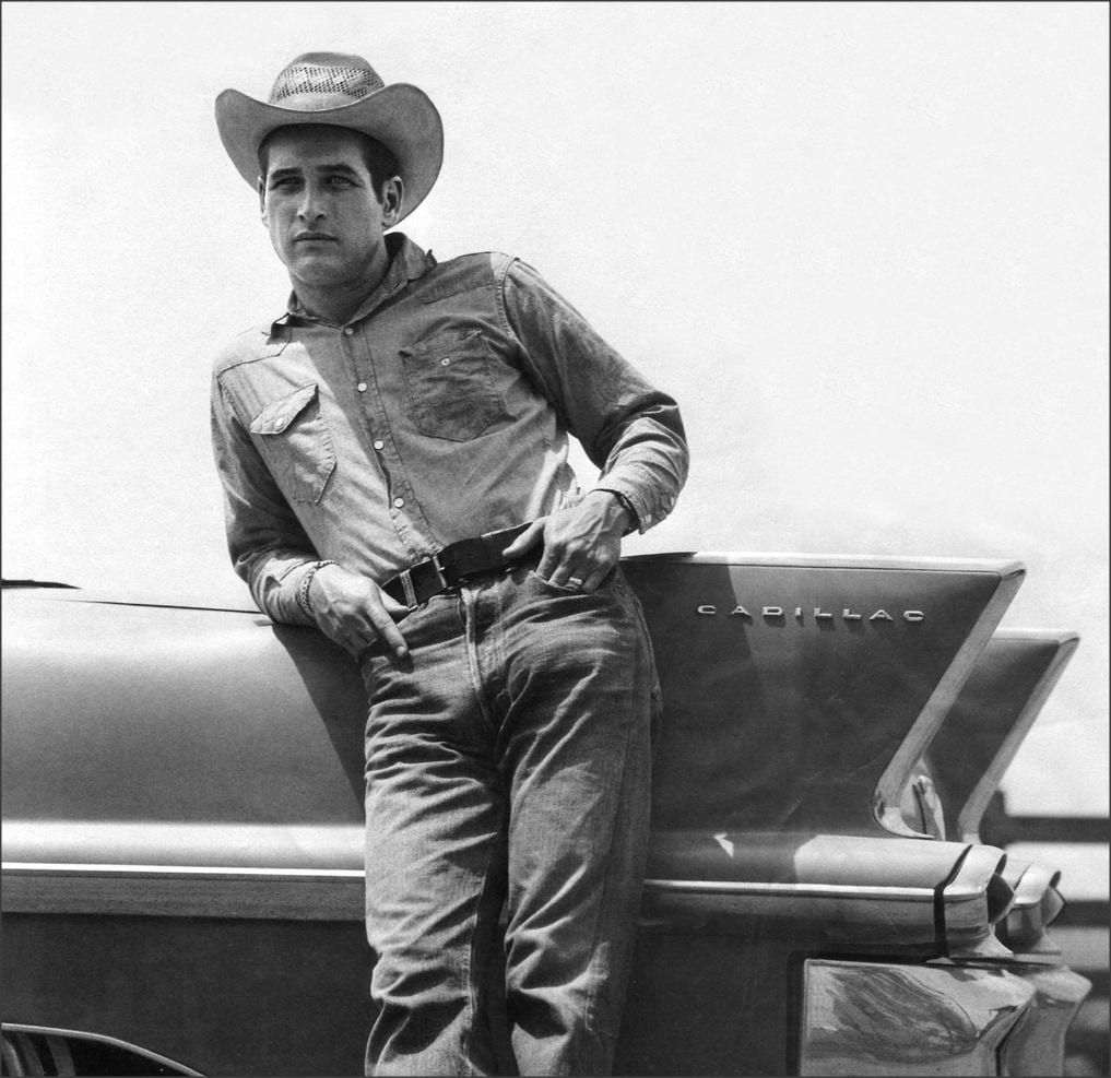 Paul Newman leans against a Cadillac
